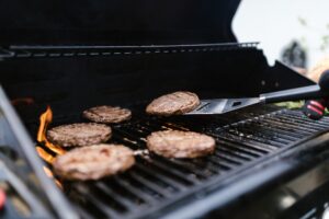 barbecue con hamburger e paletta che gira la carne